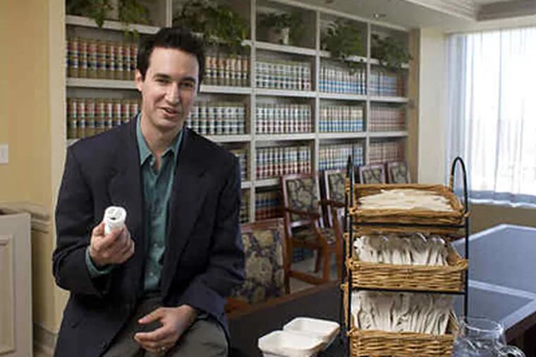 Drinker Biddle lawyer Josh Kaplowitz with a compact fluorescent bulb, among changes he initiated at the Center City law firm. He consulted on the region's Green Business Commitment. (Ed Hille / Staff Photographer)