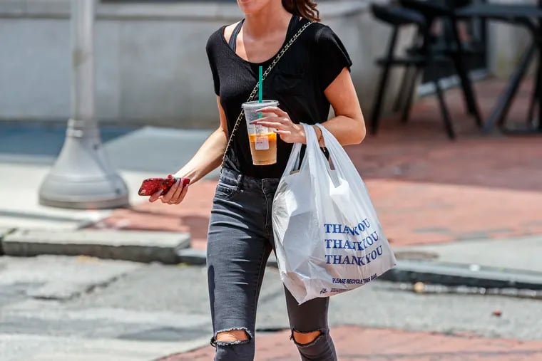 A pedestrian at 3rd and Market carries a plastic bag on June 20, 2019.