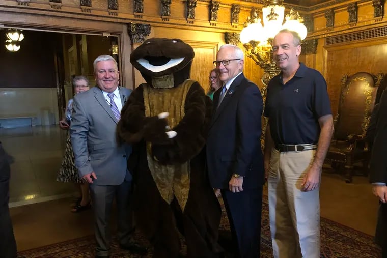 A person in a hellbender costume with, from left to right, Sen. Mike Folmer (R., Lebanon); Sen. Gene Yaw (R., Lycoming); and Sen. John Gordner (R., Columbia), at the State Capitol for a bill signing to make the Eastern hellbender the state amphibian.