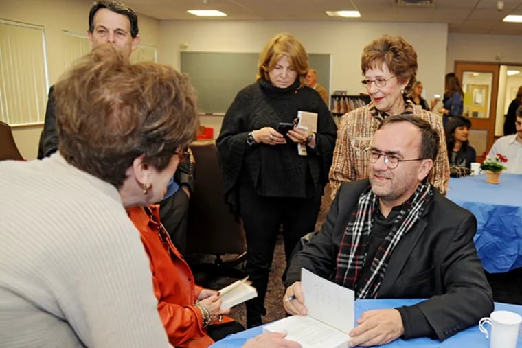 French priest Father Patrick Desbois signs copies of his book, The Holocaust by Bullets, at Gratz College in Melrose, Pa. before speaking to The Arnold and Esther Tuzman Memorial Holocaust Teach-in on Nov. 9, 2014. (CLEM MURRAY/Staff Photographer)