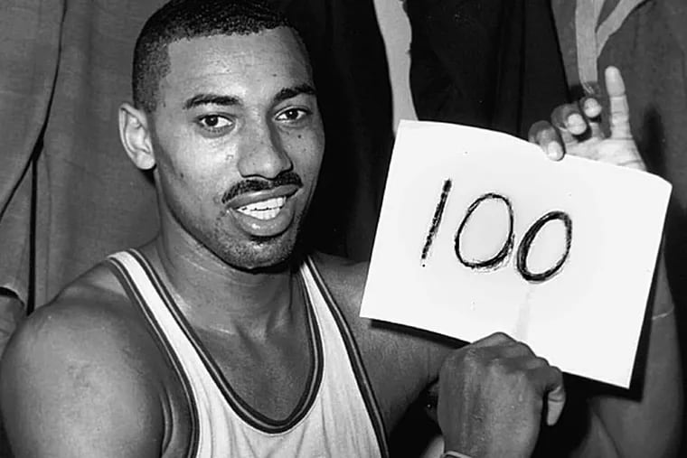 Wilt Chamberlain of the Philadelphia Warriors holds a sign reading "100" in the dressing room in Hershey, Pa., after he scored 100 points, as the Warriors defeated the New York Knickerbockers 169-147. For 50 years, Chamberlain's 100-point night has stood as one of sports magic numbers. (AP Photo/Paul Vathis, File)