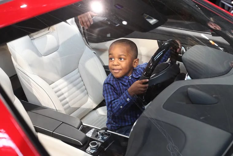 Markel Williams, 4, looks up from the drivers seat of the Mercedes SL-Roadster at his father and seems to ask, "can I keep it?" during the Philadelphia Auto Show, Jan. 31, 2015.