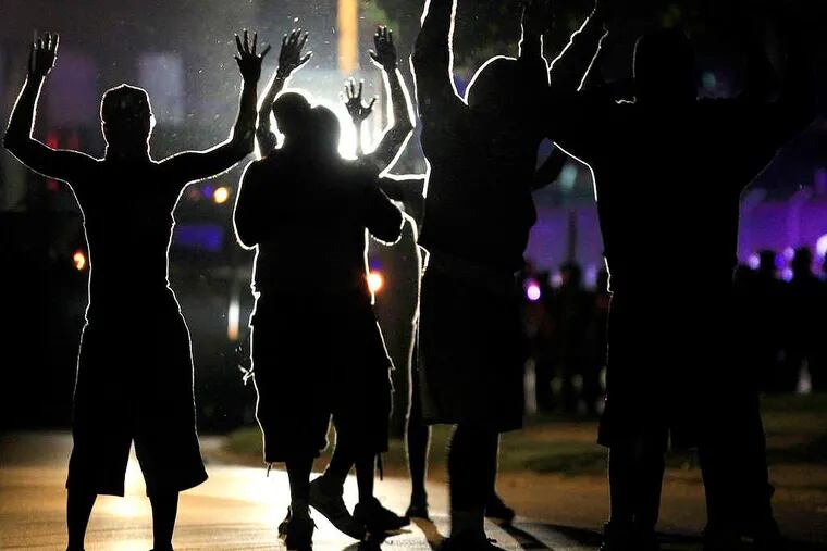 People raise their hands in the middle of the street as police wearing riot gear move toward their position trying to get them to disperse Monday, Aug. 11, 2014, in Ferguson, Mo. The FBI opened an investigation Monday into the death of 18-year-old Michael Brown, who police said was shot multiple times Saturday after being confronted by an officer in Ferguson. Authorities in Ferguson used tear gas and rubber bullets to try to disperse a large crowd Monday night that had gathered at the site of a burned-out convenience store damaged a night earlier, when many businesses in the area were looted. (AP Photo/Jeff Roberson)