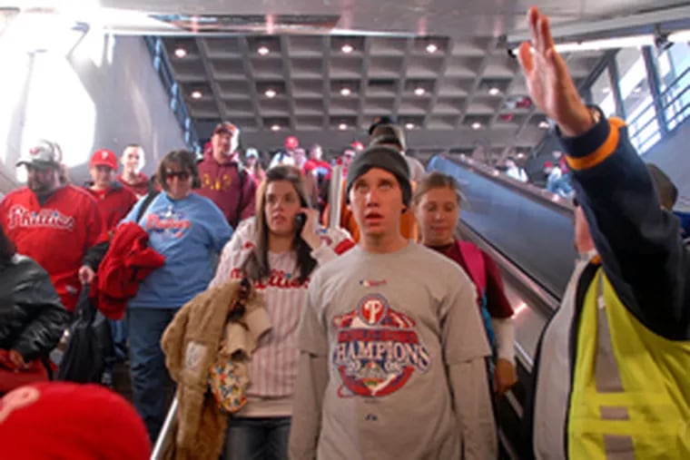A SEPTA worker guides Phillies fans to trains after leaving the stadium.