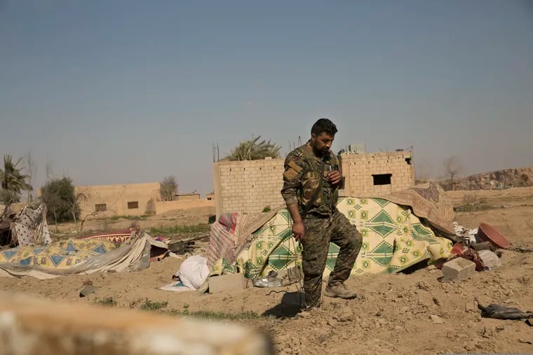 A U.S.-backed Syrian Democratic Forces (SDF) fighter walks through a tent encampment that had been occupied by Islamic State group militants, in Baghouz, Syria, Monday, March 11, 2019. A spokesman for U.S.-backed Syrian forces fighting the IS said they have made "limited advances" into the last village in eastern Syria held by the Islamic State group amid heavy fighting. (AP Photo/Maya Alleruzzo)