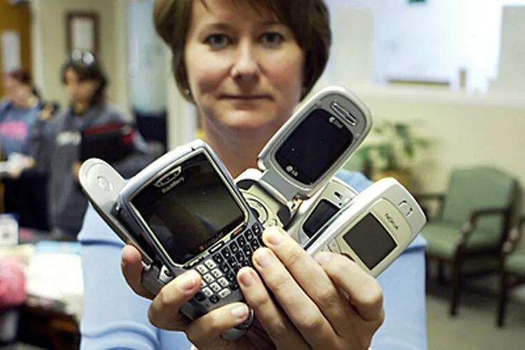 In this file photo, asst. principal Jennifer Young hold confiscated cell phones at Arlington High School in Arlington, Texas. The school implemented a policy of confiscating any cell phones students are caught having at school and the kids have to pay a fine to get them back due to text-message bullying. (Mike Fuentes/Chicago Tribune/MCT)
