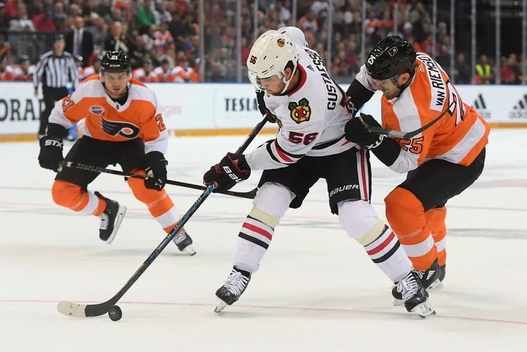 Erik Gustafsson (middle) and the Flyers' James van Riemsdyk (right) battle for the puck.