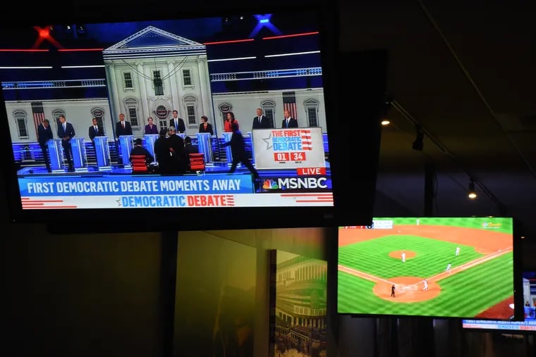 The Phillies-Mets game is on one of the TV screens as the first Democratic presidential primary debate is 90 seconds from starting, at the Field House in Center City.