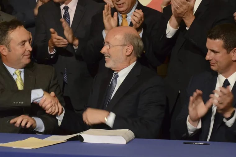In happier times, Democratic Gov. Tom Wolf shakes hands with Senate Majority Leader Jake Corman (R., Centre) after signing legislation on June 12 to reduce long-term public pension costs. Looking on is House Majority Leader Dave Reed (R., Indiana).