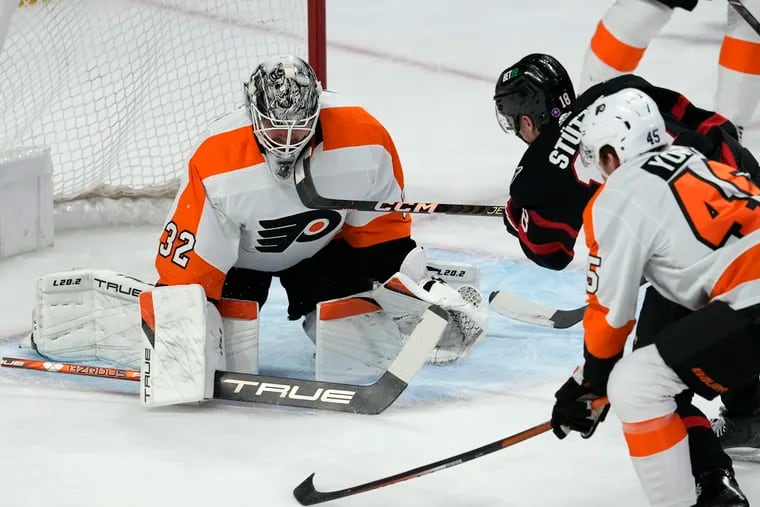 The puck hits the post behind Philadelphia Flyers goaltender Felix Sandstrom on a shot from Ottawa Senators left wing Tim Stutzle, while Flyers' Cam York defends.
