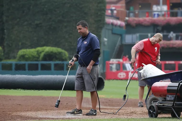 The Phillies' grounds crew flame torches the wet field before Monday night's series opener against the Washington Nationals.
