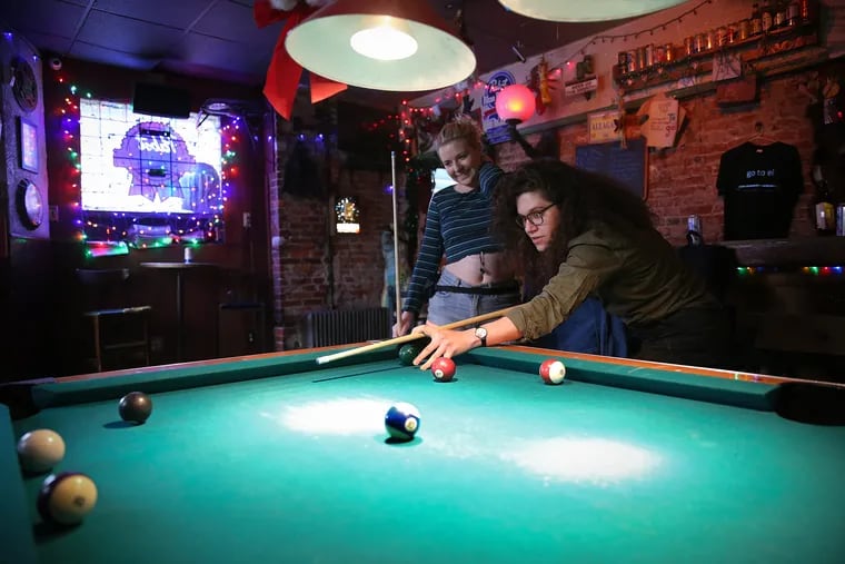 Ceire McMullen, left, and Megan Stahl, right, play a round of pool at the EL Bar before the expected shutdown on Monday. McMullen said, “We just wanted to see everyone before it all goes to s—."