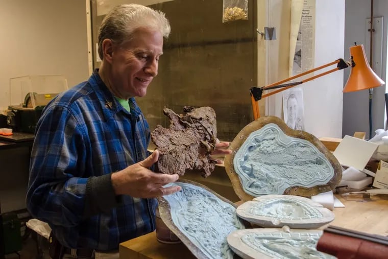 At the Academy of Natural Sciences, Fred Mullison holds a polyester cast of Tiktaalik Roseae from Arctic Canada, which he made and painted. Next to him are the corresponding silicone molds.