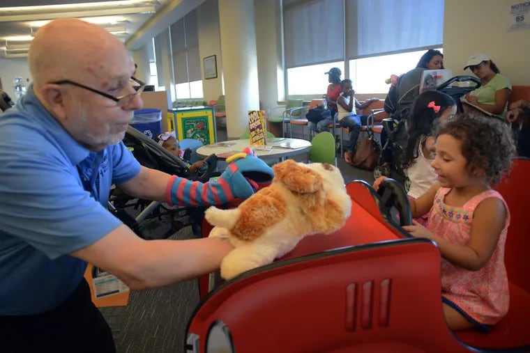 Volunteer and Penn Memory Center patient Leslie Wolff  entertains Alli-Jo Tupper (right) with his puppets at CHOP Care Network.
