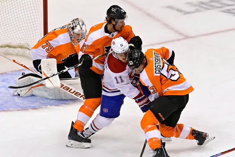 The Montreal Canadiens' Brendan Gallagher (11) battled for the puck with the Flyers' Justin Braun (61) and Shayne Gostisbehere (53) as goaltender Carter Hart looked on during the second period of an Eastern Conference playoff game Wednesday.