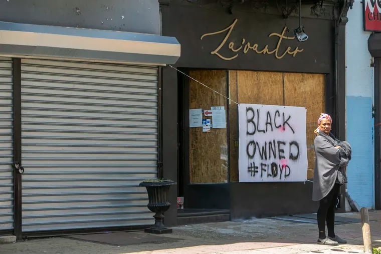 Stephanie Scurry stands in front of La'Vanter a small boutique clothing store belonging to her son and daughter on W. Venango just around corner from Germantown Ave business corridor. The windows had been boarded up from inside after they shut down during covid-19, but a sign, Black Owned #Floyd spared it from looting. Photograph from Monday, June 1, 2020. This weekend Philadelphia experienced civil unrest with protests and looting.