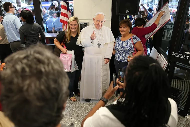 Lisa Rathbun (left) and her mother, Marianne, both of Dover, Del., pose with a cutout of Pope Francis during Friday’s grand opening of the new Wawa at Broad and Walnut Streets. The store was finished in 85 days — two months ahead of schedule. (DAVID MAIALETTI/Staff Photographer)