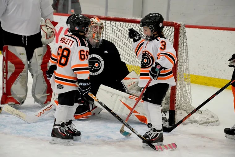 Eight-year-old J.J. Howlett (#68) from Cherry Hill and nine-year-old Josie Sweeney (#3) from Pemberton, N.J., celebrate after scoring a goal against Carter Hart. The Flyers hosted special-needs students after practice on Monday.