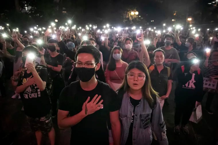 Demonstrators hold their cellphones aloft as they sing "Glory to Hong Kong" during a rally at Chater Garden in Hong Kong, Saturday, Oct. 26, 2019. Hong Kong authorities won a temporary court order banning anyone from posting personal details or photos of police officers online, in their latest effort to clamp down on the city's protest movement.