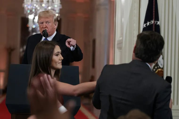 President Donald Trump watches as a White House aide reaches to take away a microphone from CNN journalist Jim Acosta during a news conference in the East Room of the White House, Wednesday, Nov. 7, 2018, in Washington.