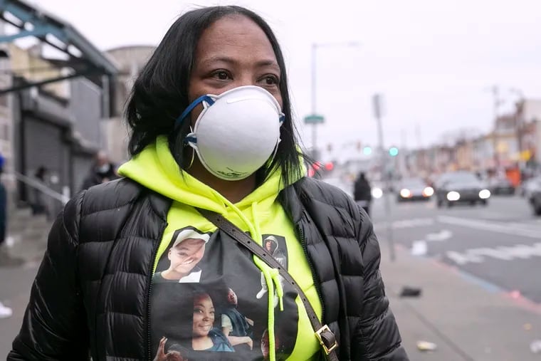 Katrina Burrell poses for a portrait while wearing a sweatshirt of her 16-year-old son, Diyaan Smith, on the corner of Allegheny and Kensington on Dec. 31, 2021. Diyaan was the last person shot and killed in Philadelphia in 2020. On the eve of the new year, Burrell and her family handed out food and supplies to those experiencing homelessness in Kensington in honor of Diyaan.