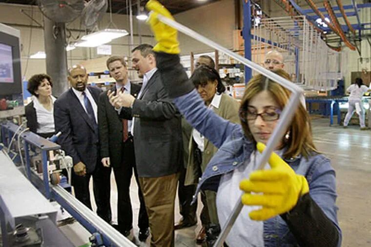 Terry Gillen, executive director of the redevelopment authority, Mayor Michael Nutter, HUD Secretary Shaun Donovan, Northeast Building Products owner Alan Levin and Councilwoman Jannie Blackwell watch Madelyn Lopez bend window spacers Friday at Northeast Building Products factory on Aramingo Avenue. (Elizabeth Robertson / Staff Photographer)