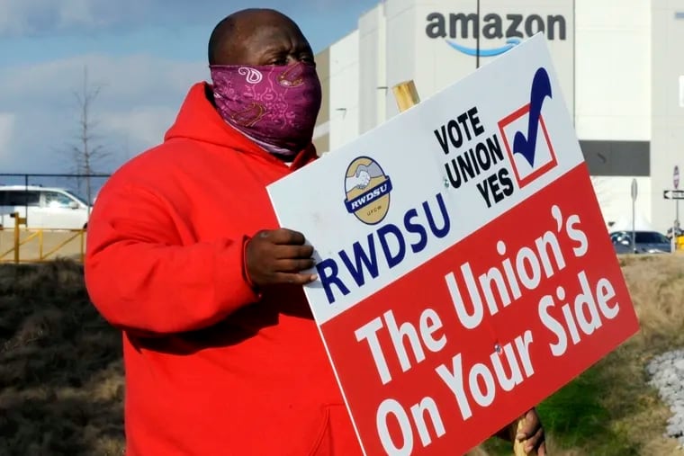 Michael Foster of the Retail, Wholesale and Department Store Union holds a sign outside an Amazon facility where labor is trying to organize workers in Bessemer, Ala., on Feb. 9, 2021. On Tuesday, Jan. 11, 2022, the National Labor Relations Board said that Amazon workers in the Bessemer facility will vote by mail in February 2022 in a re-run election to decide whether or not to unionize.