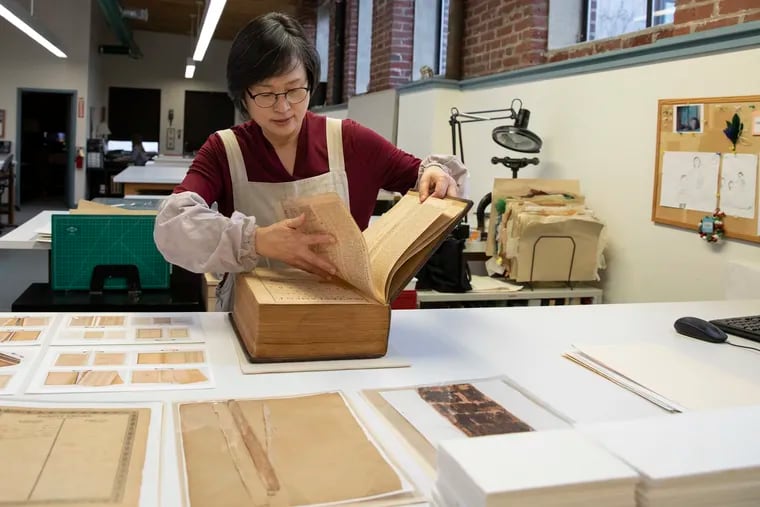 Jungohk (Theresa) Cho, who restored Betsy Ross’ family Bible, flips through its pages in the lab at the Conservation Center for Arts and Historic Artifacts.