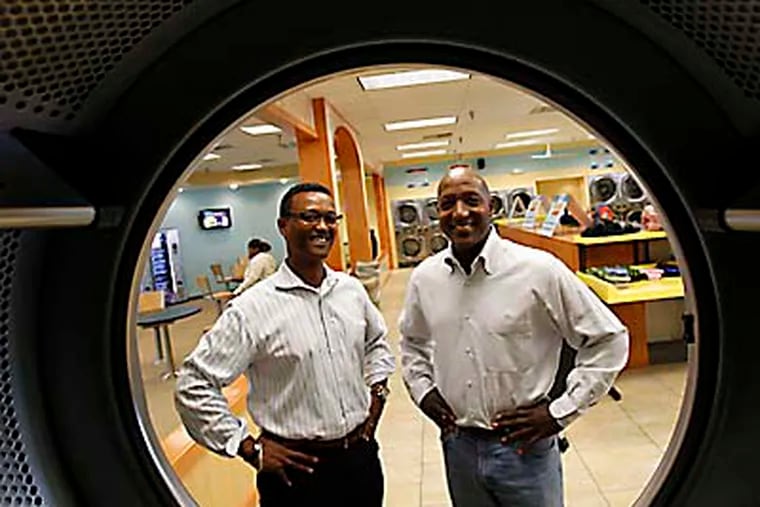 Brian Holland, left,  and Tyrone Atkins, right, pose inside their Laundry Cafe laundromat in the Olney Plaza shopping center on October 17, 2012.   ( DAVID MAIALETTI / Staff Photographer )