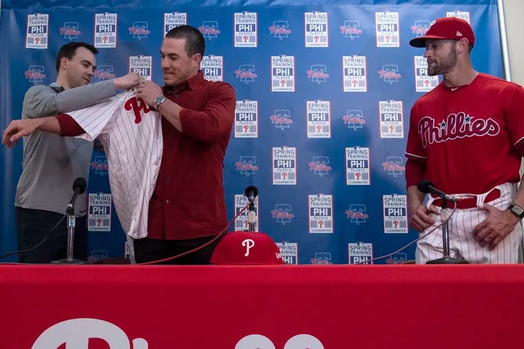 Phillies general manager Matt Klentak, left, helped catcher J.T. Realmuto, center, with his jersey when he was introduced in February 2019.