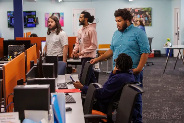 William Bell (standing), an intern in Hopeworks' training room, assists Tajon Anderson, during his fourth day. Anderson is excited to learn more about coding through his Hopeworks training.