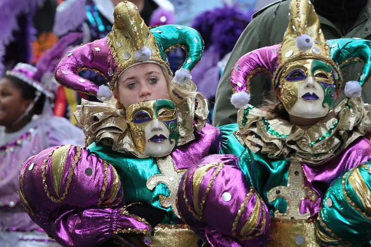 Kailee Didominic, left, takes her mask off during the Mummers Parade on New Year's Day. ( MICHAEL BRYANT / Staff Photographer )