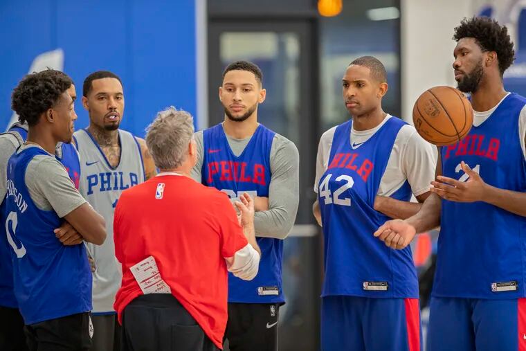 Sixers head coach Brett Brown (in red) holds a meeting on the court after practice with (from left) Josh Richardson, Mike Scott, Ben Simmons, Al Horford, and Joel Embiid.