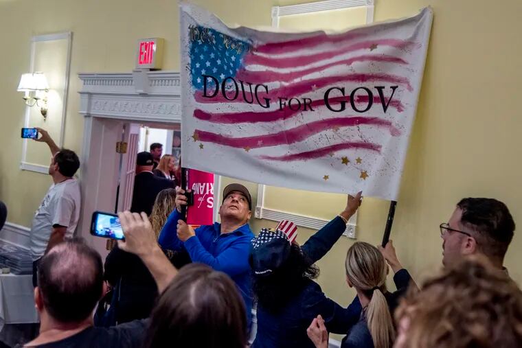Supporters raise a “Doug for Gov” banner.