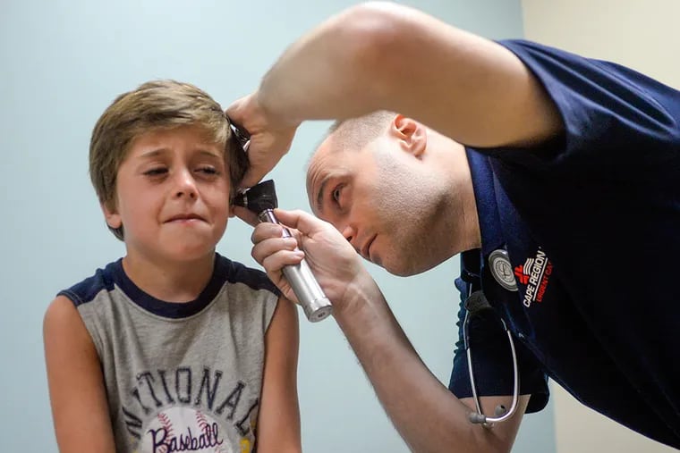 Luke Feltmann, 7, gets his ear examined by physician Joe Talotta at Cape Regional Urgent Care in Cape May Court House. (BEN MIKESELL / Staff Photographer)