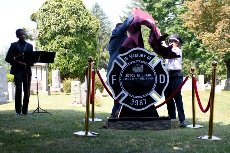 Jim Lee, of Lee Monument Co., and Capt. Lisa Forrest, president of Club Valiants, unveil the memorial headstone in memory of fallen firefighter Lt. Joyce Michelle Craig, during a ceremony for family, friends and firefighters at Ivy Hill Cemetery, in Philadelphia on Saturday.