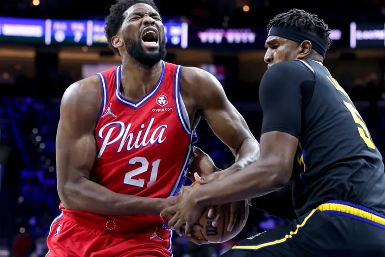 Joel Embiid, left, of the Sixers battled for the ball with Kevin Looney of the Warriors.