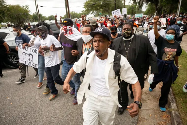 Malik Muhammad, center, joined a group of people marching from the Glynn County Courthouse in downtown to a police station after a rally to protest the shooting of Ahmaud Arbery on Saturday.