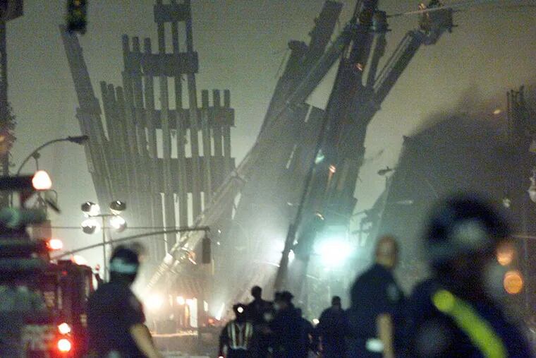 Shortly after the terrorist attacks on New York City, emergency workers walk past the remnants of a building next to what used to be the World Trade Center.