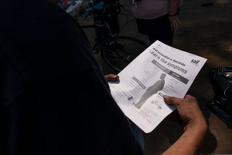 A man reads an informational handout about heat stroke.