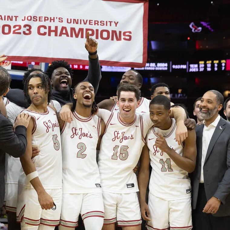 St. Joseph's celebrates as the championship banner is lowered behind them after their 74-65 win over Temple on Saturday at the Wells Fargo Center.
