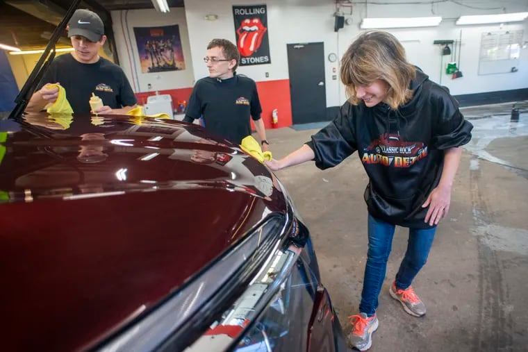 Nicole Varano (right), of Doylestown, waxes a vehicle while working with Kevin Kristich (center), of Churchville, and Ian Damiani, of Doylestown, at Classic Rock Auto Detailing in Richboro. The company was founded by two fathers who wanted to create work for their neurodivergent sons and others with disabilities.