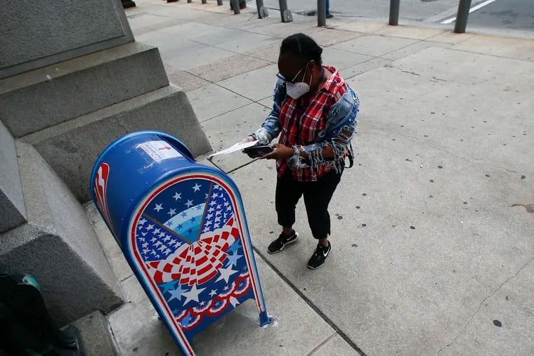 A voter prepares to drop off their ballot into a drop box at Philadelphia City Hall during May's primary election.