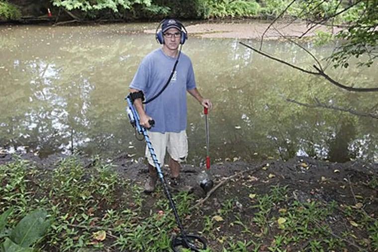 Neil Schwartz with his metal-detecting equipment searches for so-called Henning nickels July 4 on the banks of the Cooper River in Pennypacker Park in Haddonfield. (Steven M. Falk/Staff)