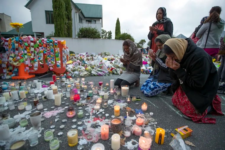 People mourn at a makeshift memorial site near the Al Noor mosque in Christchurch, New Zealand, Tuesday, March 19, 2019. Streets near the hospital that had been closed for four days reopened to traffic as relatives and friends of the victims of last week's mass shootings continued to stream in from around the world. (AP Photo/Vincent Thian)