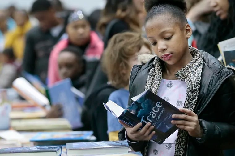 Kacia Gibson, 9,  reads a book while shopping at the African American Children's Book Fair at the Community College of Philadelphia on Feb.1, 2020.
