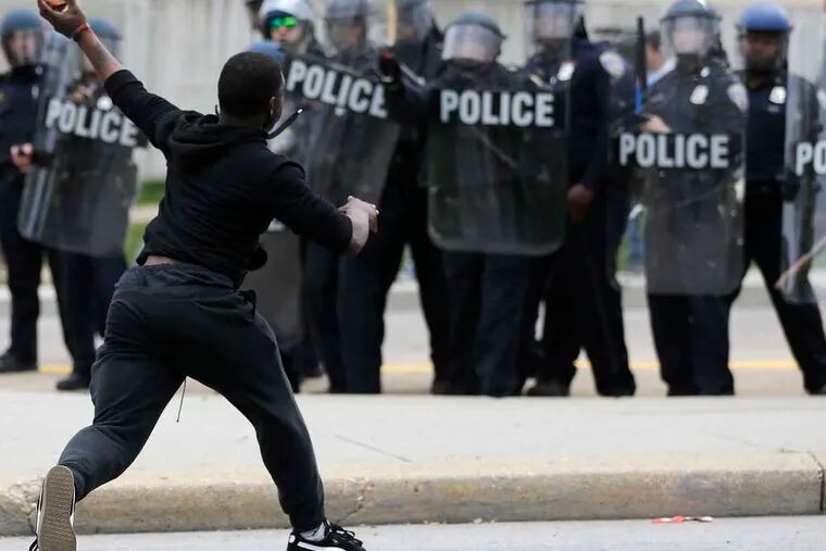 PATRICK SEMANSKY / ASSOCIATED PRESS A protester in Baltimore confronts police in riot gear during a tumultuous day.