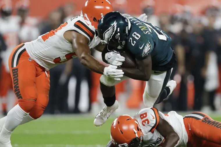 Eagles running back Wendell Smallwood runs with the football against Cleveland Browns linebacker Mychal Kendricks (left) and defensive back T.J. Carrie during the second-quarter in a preseason game at FirstEnergy Stadium in Cleveland on Thursday, August 23, 2018. YONG KIM / Staff Photographer
