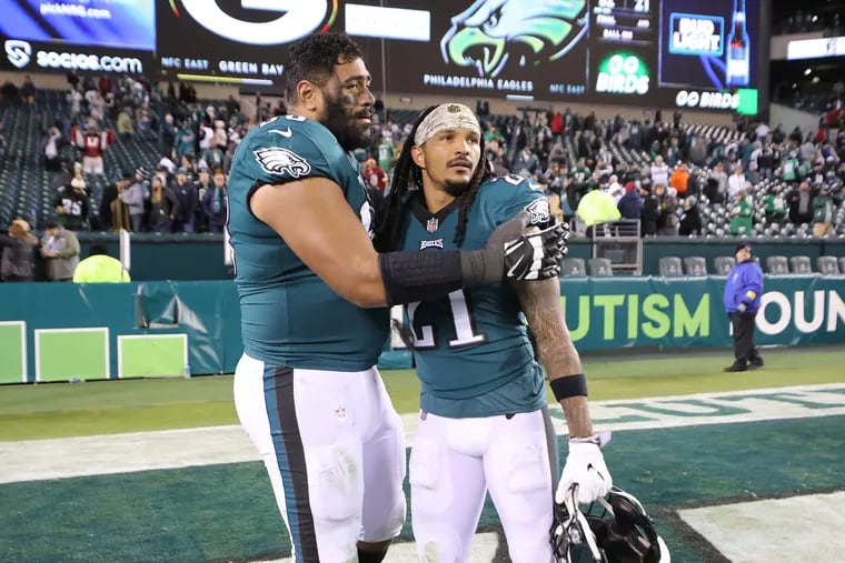 Eagles offensive tackle Jordan Mailata (left) and safety Andre Chachere embrace after the Eagles fell to the Commanders, 32-21, at Lincoln Financial Field on Monday.