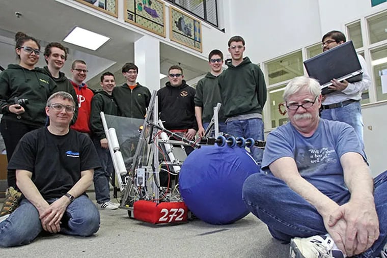 Frank Larkin, right, a principal engineer for Comcast’s National Engineering team, poses with students, their robot and mentors John Cross (left), president of ASI Technologies, and Sreekanth Uppala, (right with laptop), Comcast principal technical architect, at Lansdale Catholic High School on Feb. 17, 2014.  ( DAVID M WARREN / Staff Photographer )